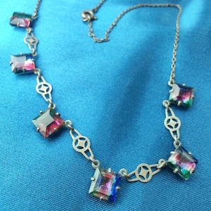 May include: A silver necklace with a delicate chain and square-shaped iridescent gemstones. The necklace has a clasp closure.