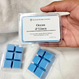 May include: A pack of blue soy wax melts with the text "BLACK PEARL SCENTS Ocean & Linen Soy wax melts | Handcrafted in Alabama Focus on fragrance | 40 hrs 2.7 Oz | 77 g"