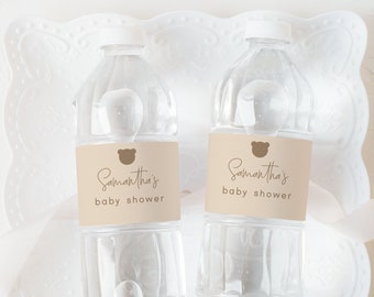May include: Two clear plastic water bottles with brown paper labels that say "Samantha's Baby Shower" on a white lace doily.