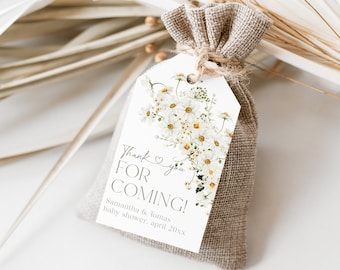 Op de afbeelding: Een witte cadeauzak met een label waarop staat "Bedankt voor het komen!" met een bloemenontwerp en de tekst "Samantha & Tomas Baby Shower, april 20XX"