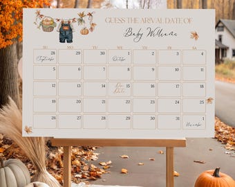 Op de afbeelding: Een houten ezel toont een beige kalender met de tekst "GUESS THE ARIVAL DATE OF Baby Willene." De kalender is versierd met herfstthema-illustraties. Pompoenen en herfstbladeren staan op de voorgrond.