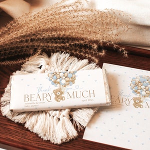 May include: A brown teddy bear holding onto blue and gold balloons. The chocolate bar wrapper says "Thank you Beary Much" with the date "April 20xx".
