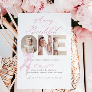 May include: A white invitation card with the text "Avery is a Bowtiful ONE" and three photos of a baby girl. The invitation is decorated with pink flowers and a pink ribbon. The text includes the date, time, and location of the event.