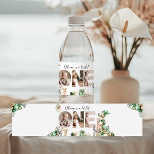 May include: A clear water bottle with a custom label that reads "Oliver is a Wild ONE." The label features photos of a baby, along with animal illustrations and decorative greenery. The bottle is displayed with a matching banner.