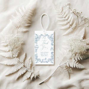 May include: A white thank you tag with blue floral border and illustrations of a hot air balloon, teddy bear, and rocking horse. The text reads "Thank You Avery & David Baby Shower March 20XX".
