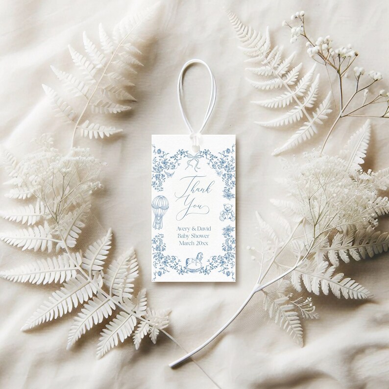 May include: A white thank you tag with blue floral border and illustrations of a hot air balloon, teddy bear, and rocking horse. The text reads "Thank You Avery & David Baby Shower March 20XX".