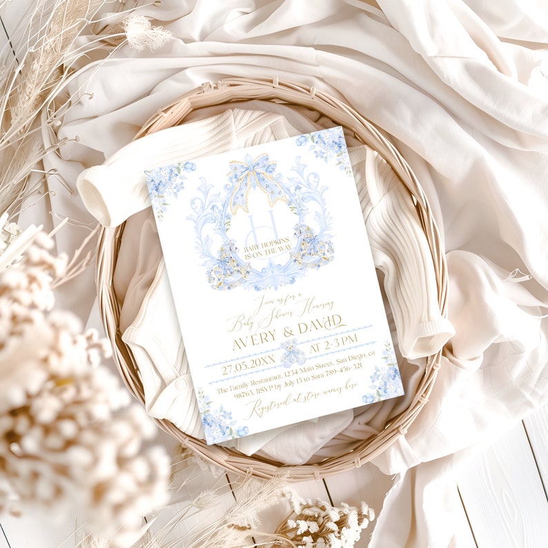 Op de afbeelding: Een blauwe en gouden babyborrel uitnodiging met een bloemenontwerp. De tekst luidt "Doe mee met ons voor een Babyborrel ter ere van Avery & David 27.05.20XX van 14:00 tot 15:00 uur De Familie Residentie 1234 Main Street, San Diego, CA 8765. RSVP v&oacute;&oacute;r 15 mei aan Sara 789-456-320 Geregistreerd bij stay away biz"