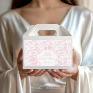 Könnte beinhalten: Weiße Babyparty-Geschenkbox mit einem rosa Toile-Muster mit Giraffen und anderen Tieren. Die Box hat einen Griff und ein Etikett mit der Aufschrift "AVERY & TOMAS Baby Shower September 27th, 2025."