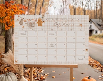 May include: A baby shower calendar with a plaid design and autumn decorations. The calendar reads "Guess the Arrival Date of Baby Williams." The calendar is displayed on a wooden easel, with pumpkins and fall foliage in the foreground.
