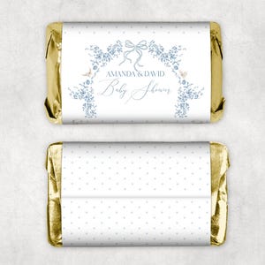 May include: Gold foil-wrapped chocolate bar with a white wrapper featuring a blue floral design and the text "Amanda & David Baby Shower". The back of the wrapper has a white background with blue polka dots.