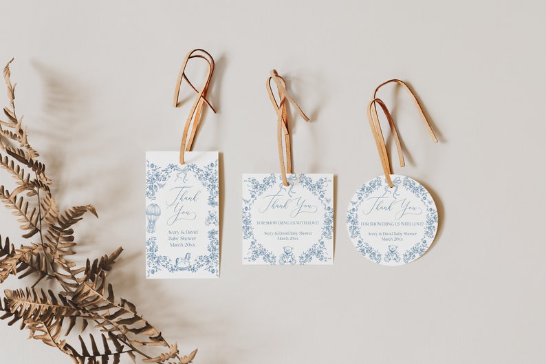 May include: Three blue and white thank you tags with a floral design and the text "Thank You" for a baby shower. The tags are tied with brown twine.