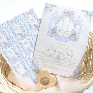 Op de afbeelding: Een blauwe en gouden babyborrel uitnodiging met een bloemenontwerp en een schommelpaard. De uitnodiging luidt "Baby Shower Honoring Avery & David 27.05.20XX van 14:00-15:00 uur The Family Restaurant, 1234 Main Street, San Diego, CA 98765. RSVP v&oacute;&oacute;r 15 mei naar 789-45-320.  RSVP en winkelnamen hier."