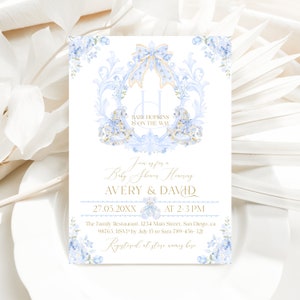 Op de afbeelding: Een blauwe en gouden babyborrel uitnodiging met een monogram van de letter H, een strik en bloemmotieven. De tekst luidt "Baby Hopkins is on the way" en "Join us for a Baby Shower Honoring Avery & David". De datum en tijd van de babyborrel zijn vermeld als "27.05.20XX om 14:00-15:00 uur". De locatie is "The Family Restaurant, 1234 Main Street, San Diego, CA 98761". De RSVP-informatie is "RSVP v&oacute;&oacute;r 15 juli aan Sara 789-456-321". Onderaan de uitnodiging staat "Registered at store names here".
