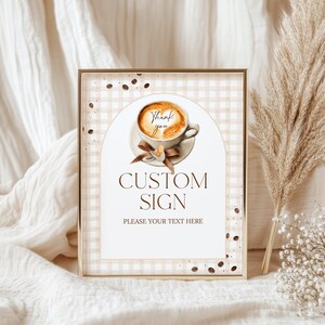 Puede incluir: Un letrero personalizado enmarcado con un borde dorado. El letrero presenta una ilustración de acuarela de una taza de café con las palabras "Thank you" en la espuma. El letrero también incluye las palabras "CUSTOM SIGN" y espacio para texto.