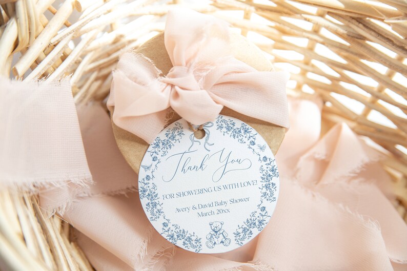May include: A round thank you tag with a blue floral border and a teddy bear illustration. The tag says "Thank you for showering us with love! Avery & David Baby Shower March 20xx".