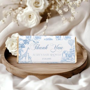 May include: Blue and white thank you favor box with a giraffe, elephant, and hot air balloon design. The text reads "Thank You Avery's Baby Shower 27.03.20XX".