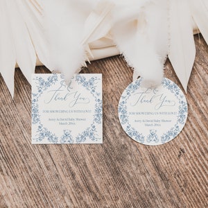 May include: Two blue and white thank you tags with a floral border and a teddy bear design. The text on the tags reads "Thank You for showering us with love! Avery & David Baby Shower March 20xx".