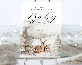 Könnte beinhalten: Ein Willkommensschild für eine Babyparty auf einer Staffelei. Das Schild zeigt eine Aquarell-Winterlandschaft mit Hirschen und Kiefern. Der Text lautet "Willkommen bei Samantha & Tomas" und "Baby Shower" mit einem Datum.