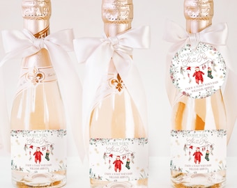 Puede incluir: Tres botellas de champán con etiquetas que dicen "Pop It When She Pops". Cada botella está adornada con una cinta blanca y una etiqueta con un diseño temático de bebé y el texto "Enjoy a toast when baby Williams arrives."