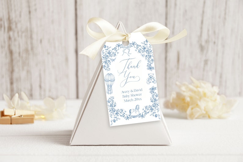 May include: A white thank you tag with blue floral border and illustrations of a hot air balloon, teddy bear, and rocking horse. The text reads "Thank You Avery & David Baby Shower March 20XX".