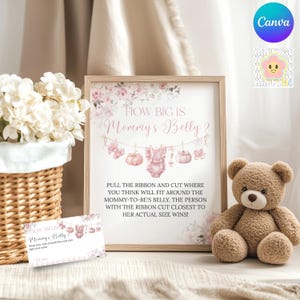 Può includere: Un gioco per baby shower incorniciato con il testo "How Big Is Mommy's Belly?" e illustrazioni di vestiti per bambini e zucche. Un orsacchiotto e una piccola carta sono accanto alla cornice. Un cesto di fiori bianchi è a sinistra.