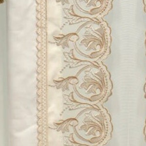 May include: Cream-colored curtain panel with intricate embroidered floral and scrollwork design in a light brown hue. The panel features a scalloped edge and a decorative tassel.