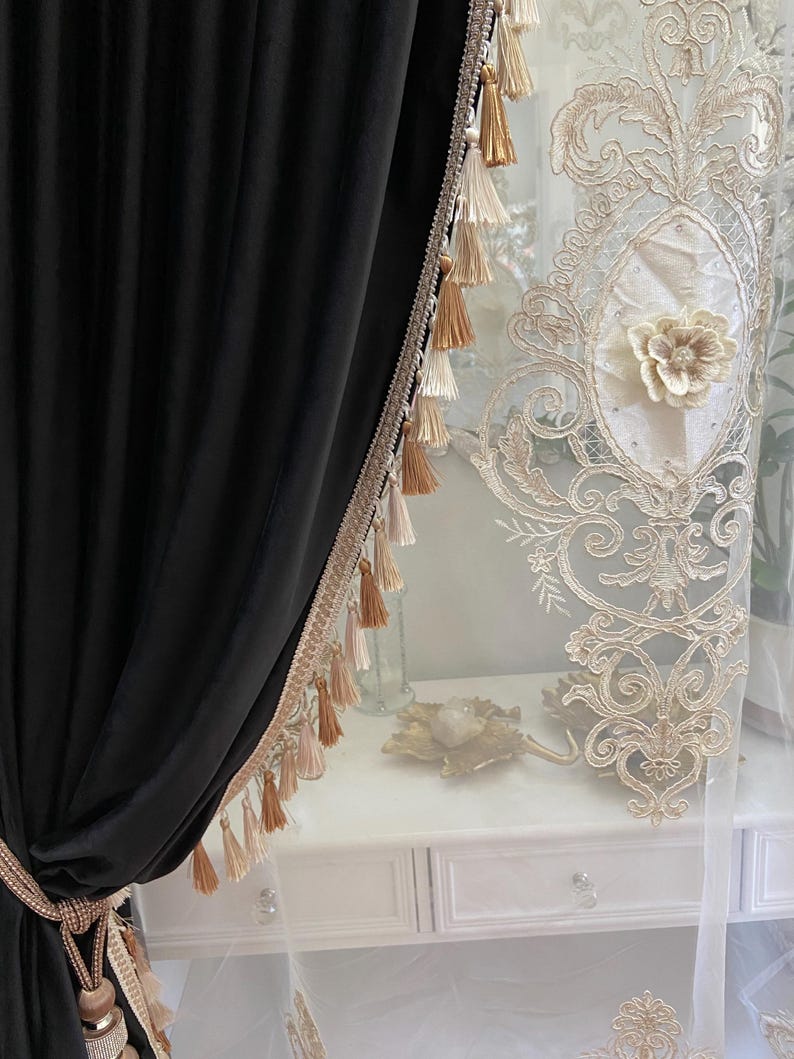 Pu&ograve; includere: Tenda in velluto nero con finiture decorative e nappe. A destra &egrave; visibile una tenda trasparente con un motivo floreale ricamato. Le tende sono adatte per un soggiorno o una camera da letto.