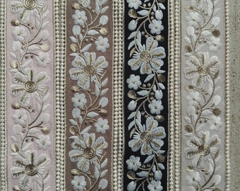 Pode incluir: Close-up de fitas decorativas com bordados florais. As fitas apresentam uma variedade de cores, incluindo rosa, castanho, preto e branco. Cada fita tem um design diferente, com flores e folhas bordadas.