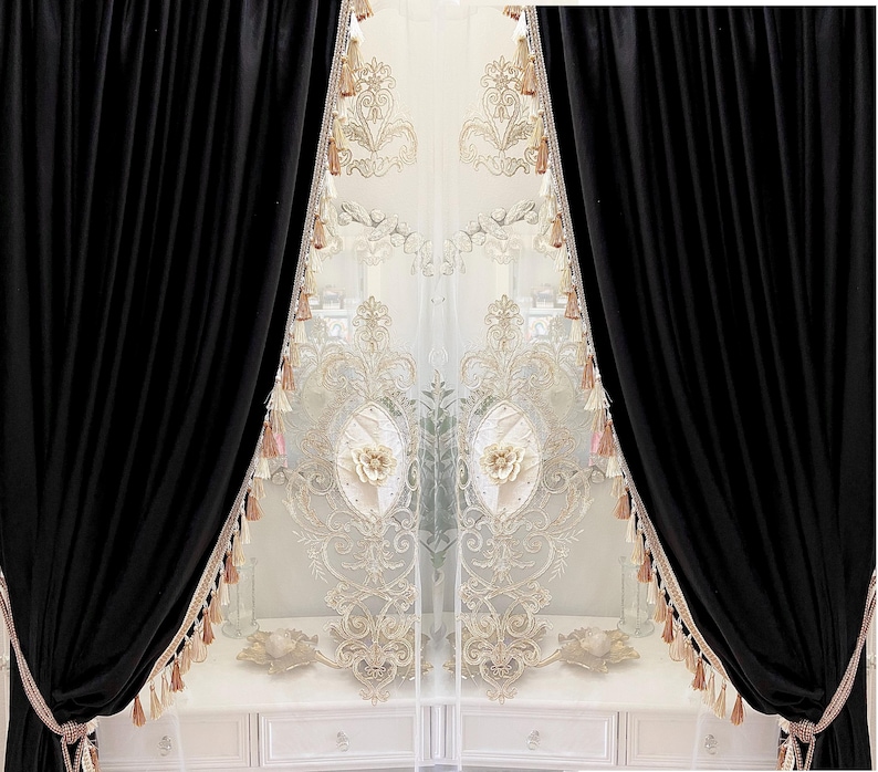 Pu&ograve; includere: Eleganti tende in velluto nero che incorniciano pannelli trasparenti ricamati. I pannelli trasparenti presentano disegni floreali e a volute con accenti oro e crema. Nappe adornano i bordi, aggiungendo un tocco di lusso al trattamento della finestra.