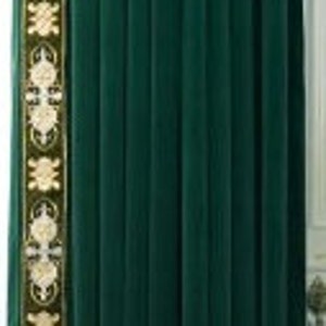 May include: Dark green velvet curtain with a decorative border. The border has an ornate design in gold and olive green. The curtain hangs from a gold rod. The curtain is partially drawn, revealing a white door frame.
