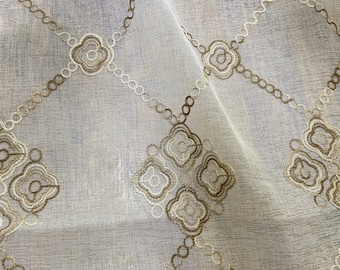Può includere: Tessuto bianco trasparente con un motivo geometrico ricamato in oro. Il design presenta maglie di catena interconnesse e forme floreali, creando una trama delicata ed elegante. Il tessuto è leggermente traslucido.