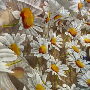 Puede incluir: Tela transparente con un estampado floral de margaritas blancas con centros amarillos y marrones. La tela es ligera y permite que el fondo sea parcialmente visible. Ideal para proyectos de costura o manualidades.