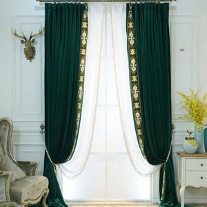 May include: Luxurious emerald green velvet curtains with gold embroidered trim and white sheer panels. The curtains are draped and tied back, creating a sophisticated window treatment. The design includes a decorative gold curtain rail.