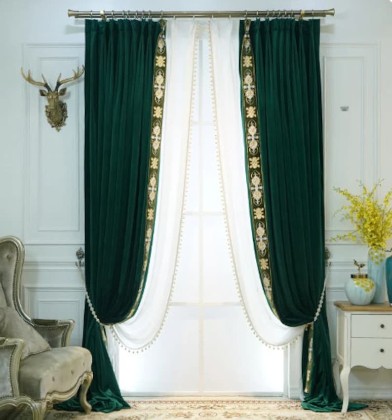 May include: Luxurious emerald green velvet curtains with gold embroidered trim and white sheer panels. The curtains are draped and tied back, creating a sophisticated window treatment. The design includes a decorative gold curtain rail.