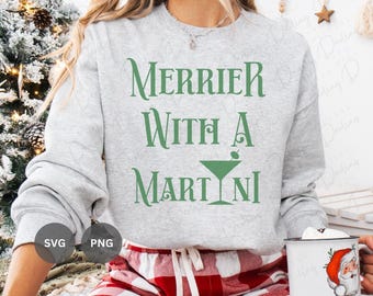 May include: A grey sweatshirt with the text "Merrier with a Martini" in green lettering. The text is accompanied by a green martini glass with an olive.