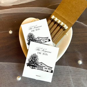 Puede incluir: Un plato en forma de coraz&oacute;n contiene dos cajas de cerillas y una caja de cerillas. Las cajas de cerillas son blancas con una ilustraci&oacute;n negra de un &aacute;rbol y un edificio, y el texto "The Fergusons EST 2025". La caja de cerillas es marr&oacute;n con cerillas.