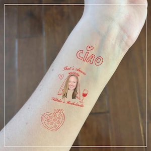 May include: Red temporary tattoo with the word "CIAO" and the phrase "That's Amore". Includes a portrait of a woman in a veil, a wine glass, and a heart-shaped pizza. The tattoo is designed for a bachelorette party.