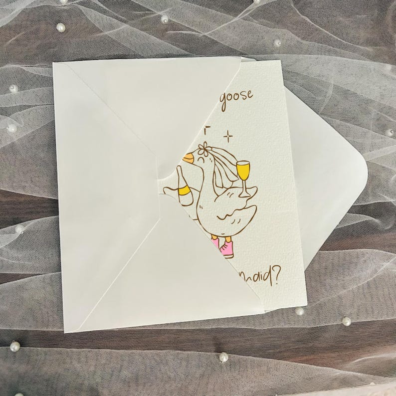 May include: White greeting card with a cartoon goose illustration holding a champagne bottle and a glass of wine. The text "goose maid?" is handwritten on the card. The card is inside a white envelope.