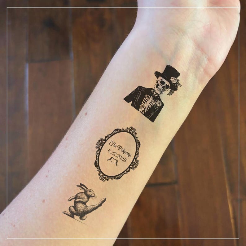 May include: Three temporary tattoos on a person's arm. The tattoos are black and white and feature a skeleton in a top hat, a rabbit, and a framed design with the text "The Ridgeways 6.22.2025".