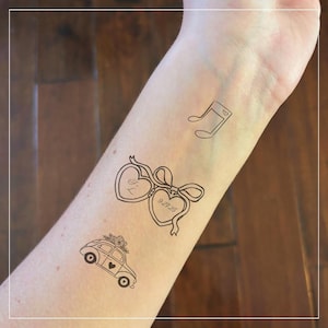 Peut inclure: Un tatouage temporaire avec trois motifs&nbsp;: une note de musique, un m&eacute;daillon avec l&rsquo;inscription &laquo;&nbsp;I'L&nbsp;&raquo; et la date &laquo;&nbsp;9.27.23&nbsp;&raquo;, et une voiture ancienne avec un sapin de No&euml;l sur le toit.