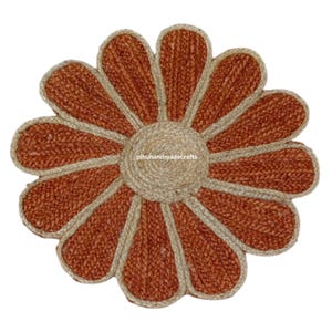 K&ouml;nnte beinhalten: Ein runder Jute-Teppich in Braun und Beige in Form einer Blume mit 10 Bl&uuml;tenbl&auml;ttern. Der Teppich hat einen Mittelkreis und die Bl&uuml;tenbl&auml;tter sind beige umrandet.