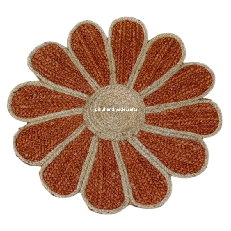 K&ouml;nnte beinhalten: Ein runder Jute-Teppich in Braun und Beige in Form einer Blume mit 10 Bl&uuml;tenbl&auml;ttern. Der Teppich hat einen Mittelkreis und die Bl&uuml;tenbl&auml;tter sind beige umrandet.