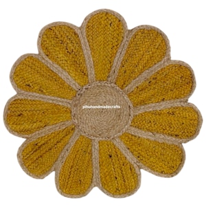 K&ouml;nnte beinhalten: Eine gelbe und naturfarbene Jute-Fu&szlig;matte in Blumenform mit einem gewebten Zentrum. Der Text "pihuhandmadecrafts" ist in der Mitte der Matte sichtbar.