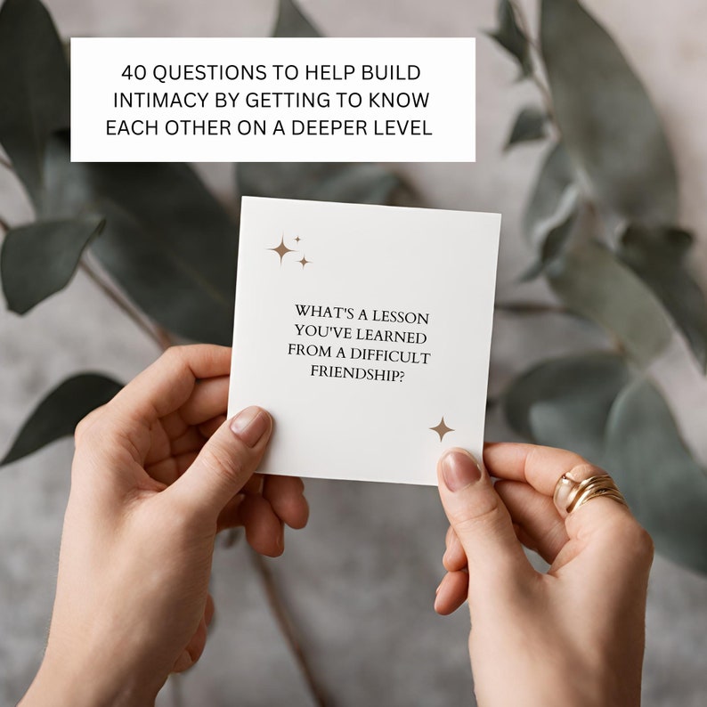 May include: A white card with gold stars and the text "What's a lesson you've learned from a difficult friendship?"  The card is being held by a person's hands.