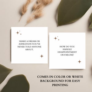 May include: Two white cards with brown text and stars. The first card says "Share a dream or aspiration you've never told anyone about." The second card says "How do you handle disappointment or failure?" The text below the cards says "Comes in color or white background for easy printing."