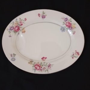 May include: A white oval serving platter with a gold rim and a floral design. The flowers are pink, red, yellow, and blue.