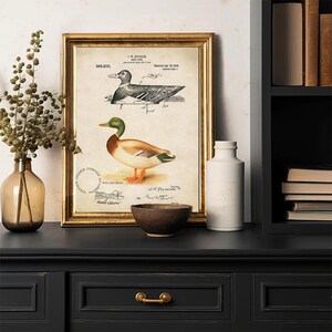 Vintage duck decoy wall art featuring a 1910 patent sketch and watercolor illustration of a mallard drake. Perfect for farmhouse, rustic, lodge, or hunting-themed decor. This antique bird print is a high-resolution digital download for instant use. Ideal for vintage art lovers, birdwatchers, or as a Father's Day gift. Styled for cottagecore, nature-inspired, or Americana interiors. Unique historical artwork to enhance your space with charm and character.