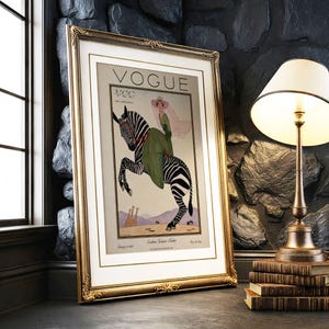 Digitally restored 1926 Vogue magazine cover titled Southern Fashions Number, featuring a stylish woman in a flowing green dress and pink hat riding a zebra in a desert landscape with giraffes and mountains. Vintage Art Deco fashion illustration digital download ideal for gallery walls, eclectic decor, and gifts for fashion history and vintage art lovers.