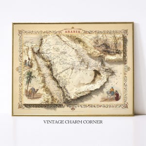 May include: Framed vintage map of Arabia with detailed topography. The map features illustrations of a camel, palm tree, and figures on horseback. The frame is gold-colored, and the map has a beige background with the word "ARABIA" at the top.