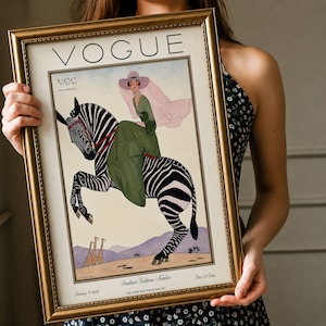Digitally restored 1926 Vogue magazine cover titled Southern Fashions Number, featuring a stylish woman in a flowing green dress and pink hat riding a zebra in a desert landscape with giraffes and mountains. Vintage Art Deco fashion illustration digital download ideal for gallery walls, eclectic decor, and gifts for fashion history and vintage art lovers.
